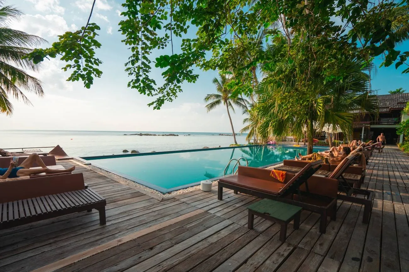 Terrasse en bois avec transats face à une eau turquoise
