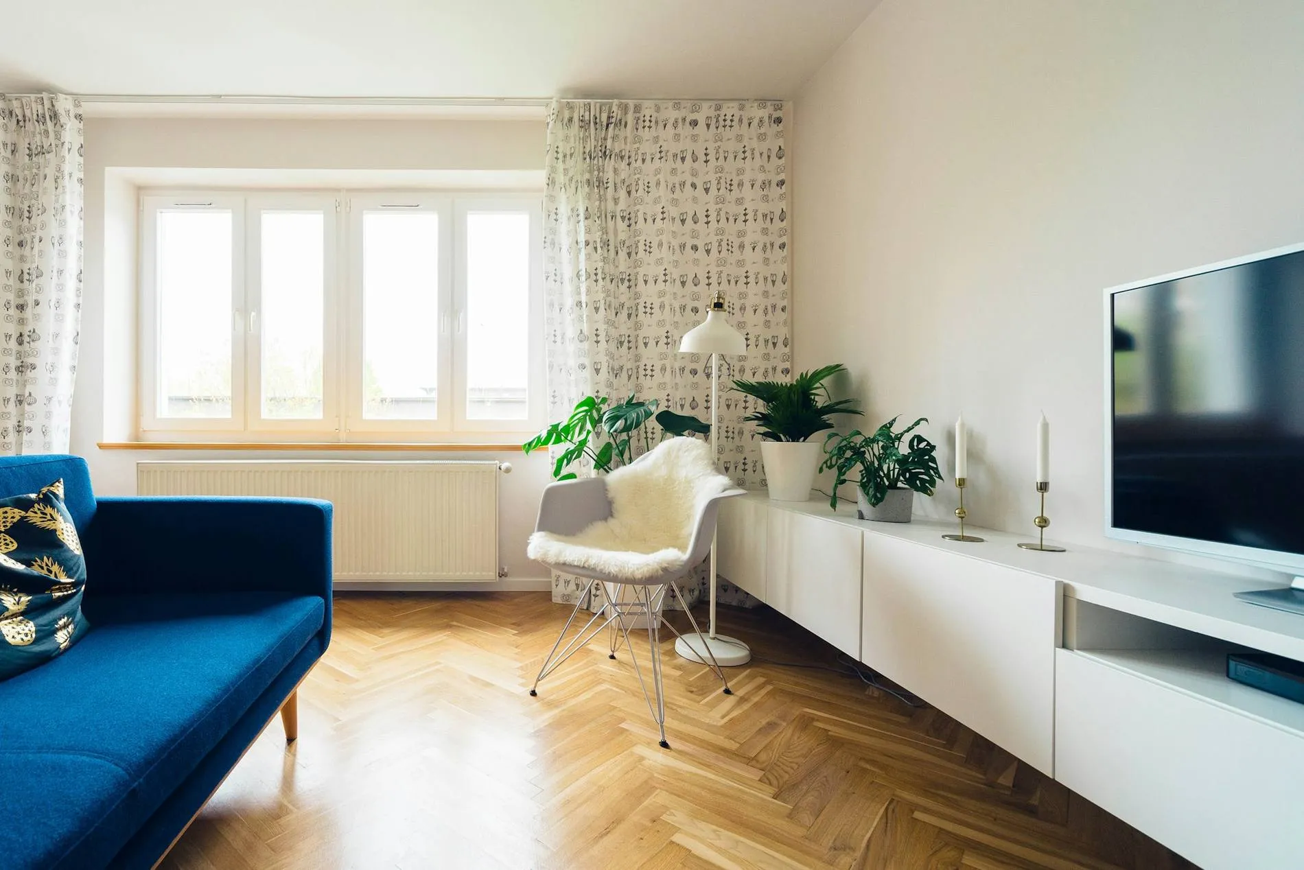 Salon lumineux avec canapé bleu et parquet en point de Hongrie