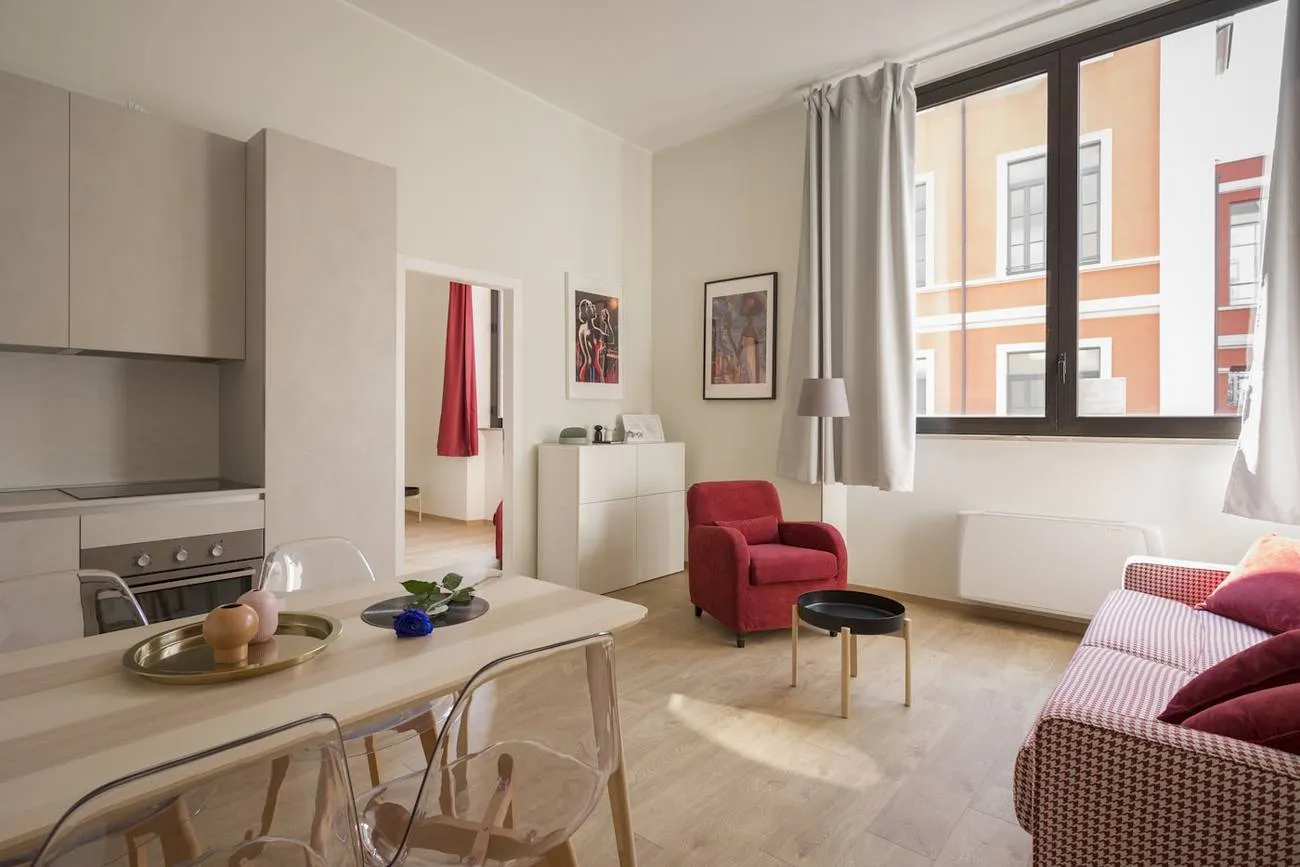 Séjour lumineux avec cuisine ouverte et fauteuil rouge